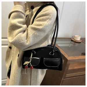 Detail of black shoulder bag with unique cherry charm and double front pockets