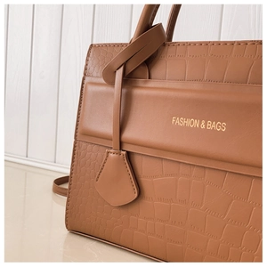 Detail of caramel brown handbag showing crocodile texture leather and golden lettering