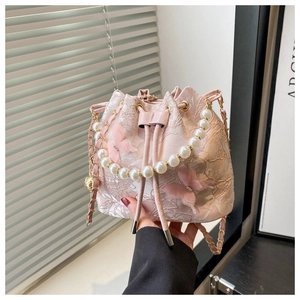 Détail du sac seau en dentelle rose avec poignée en perles et papillons en relief