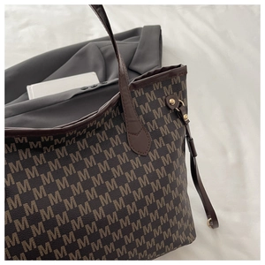 Detailed macro view of retro monogram pattern and golden metal hardware on a tote bag