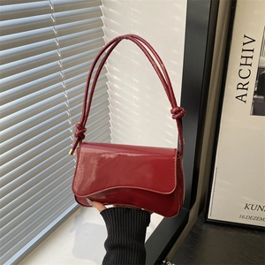 Chic burgundy patent leather underarm bag with wavy flap design and glossy finish