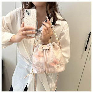 Détail du sac seau en dentelle rose avec papillons 3D et élégante poignée en perles