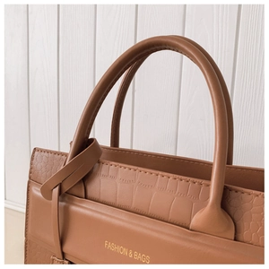 Macro shot of brown leather bag showing premium crocodile embossed texture and stitching