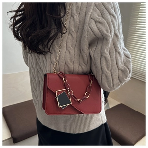 Macro detail of red textured leather crossbody bag with chic chunky chain and metal strap