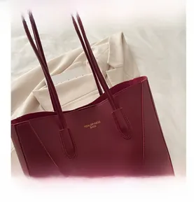 Detail view of burgundy leather tote bag with brand lettering and elegant stitching