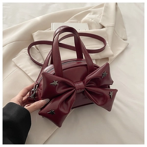 Detail of burgundy handbag with large bow and silver star metal studs on white blazer