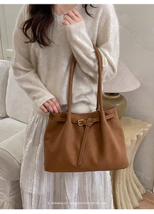 Detail of a retro brown suede tote bag with metal buckle in a cozy home setting