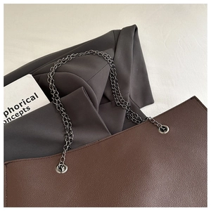 Détail du sac fourre-tout marron foncé avec texture grainée et bandoulière en chaîne
