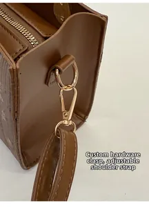 Détail de la bandoulière réglable en cuir marron avec fermoir mousqueton doré brillant