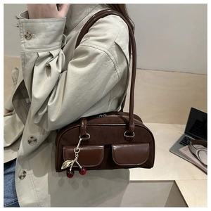 Detail of dark brown retro shoulder bag with dual front pockets and cherry pendant
