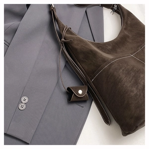 Macro detail of dark brown frosted tote bag with white stitching and mini pouch accessory