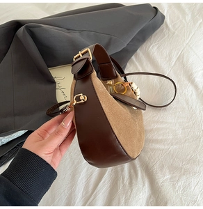 Detail of khaki suede crescent bag featuring brown leather trim and pearl charm