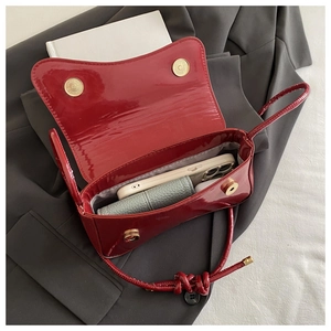 Macro view of red patent leather shoulder bag interior with golden magnetic closure