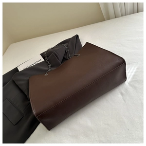 Détail d'un grand cabas en cuir marron foncé avec bandoulière chaîne et texture grainée