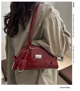 Chic red patent leather crescent shoulder bag styled as an underarm bag on a model
