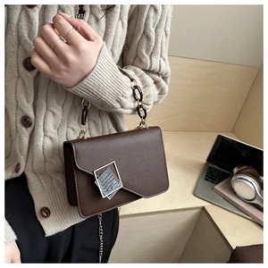 Close-up of brown crossbody bag with marble buckle and chain strap on a model