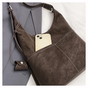Detail showing the large front pocket of a vintage brown tote bag holding a smartphone