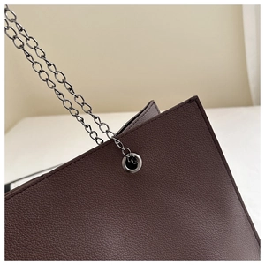 Détail du cuir grainé marron foncé avec bandoulière en chaîne et œillet métallique poli