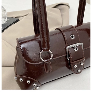 Detail der dunkelbraunen Leder-Tasche mit silbernen Nieten und metallischer Schnallenverzierung
