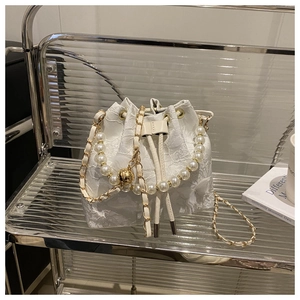Détail du sac seau en dentelle blanche avec poignée en perles et cordon de serrage