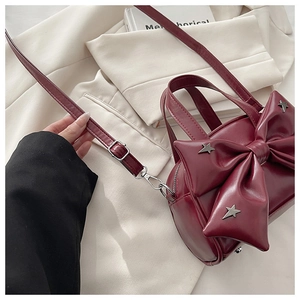 Detail of burgundy PU leather handbag featuring a large bow and star-shaped metal rivets