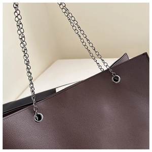 Vue rapprochée du cuir grainé et de la chaîne en métal du grand sac fourre-tout marron