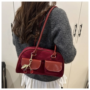 Detail of retro dark red suede shoulder bag featuring double pockets and cherry charm
