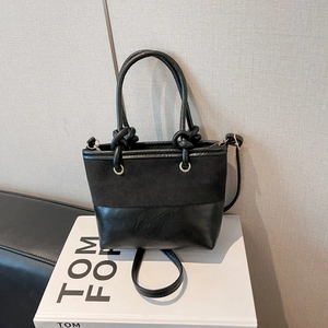 Minimalistische schwarze Beuteltasche mit Kontraststruktur, geknoteten Griffen und Golddekor