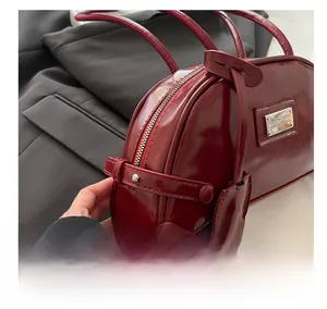 Close-up of deep red glossy patent leather handbag with silver metal logo and dual handles