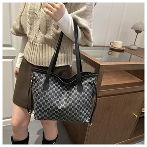Close-up of M-pattern jacquard fabric and black leather strap on a large tote bag