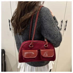 Detail of burgundy shoulder bag with dual front pockets and glossy patent leather straps