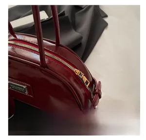 Detail of glossy wine red shoulder bag with gold zipper and premium patent leather finish