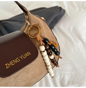 Close-up of camel suede and brown leather patchwork bag with wooden bead tassel details