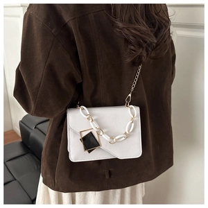 Close-up of white crossbody bag with gold chain strap and chunky acrylic chain detail