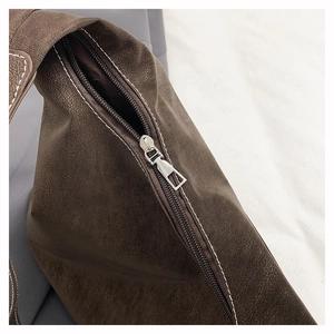 Detailed close-up of brown textured leather tote with contrast white stitching and metal zipper