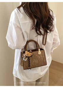 Détail du sac à main vintage marron avec cuir texturé, breloque en peluche et bandoulière