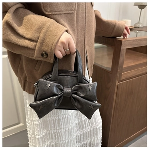 Détail du sac seau gris foncé avec un grand nœud et des rivets argentés en étoile