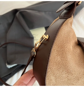 Close-up of brown leather and khaki suede stitching with gold metal chain buckle