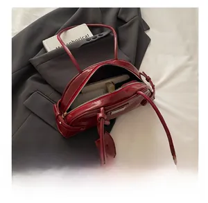 Detail shot of a red leather Boston bag showing interior capacity on black suit