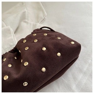 Dettaglio della texture in pelle scamosciata marrone e borchie dorate sulla borsa vintage