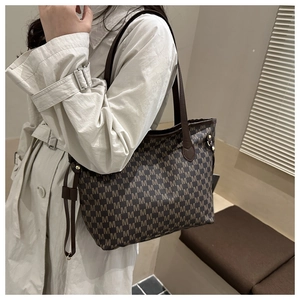 Detail view of the brown jacquard tote bag with M-pattern texture and leather handles
