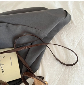Detail of dark crossbody bag with brown leather strap and soft suede interior lining