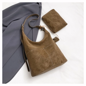 Detail of dark brown faux suede hobo bag set with contrast stitching on white fabric