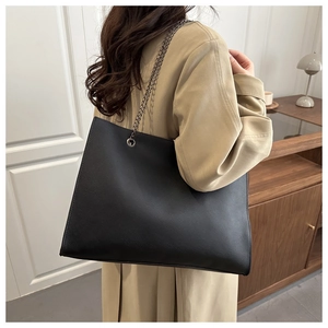 Gros plan du grand sac cabas noir en cuir grainé avec bandoulière chaîne sur un mannequin