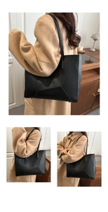 Detail view of large black tote bag with geometric stitching and metal protective studs