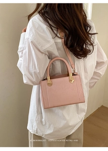 Détail du mini sac carré en cuir rose avec ferrures dorées porté en bandoulière sur l'épaule