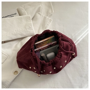 Dettaglio borsa in camoscio bordeaux con borchie dorate e spazio interno per accessori