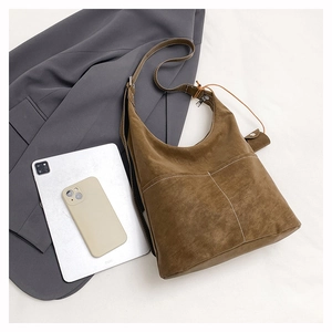 Brown suede hobo bag detail with white contrast stitching and a functional double pocket design