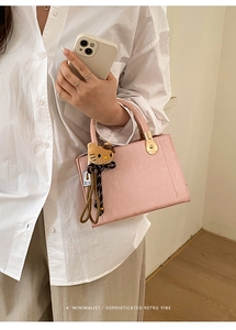 Détail du sac à main en cuir rose texturé avec charm en peluche et fermoir en métal