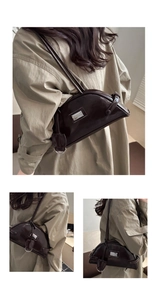 Detail view of semi-circular patent leather handbag in dark brown with silver logo plate